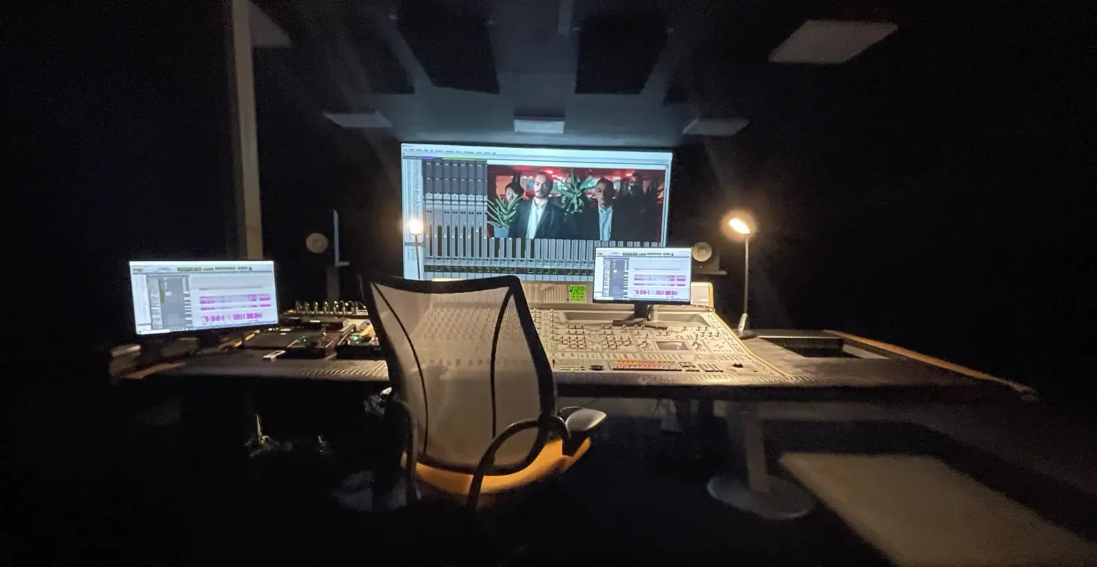Régie de post-production audio avec surface de contrôle et écran de projection